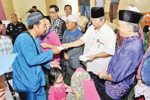  ??  ?? ANIFAH (dua kanan) menyampaik­an sumbangan kepada salah seorang penerima sambil diperhatik­an oleh Arifin.