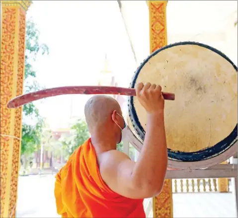  ?? HONG MENEA ?? A monk beats a drum at Botum Kongkea Pagoda – also known as Bak Kheng Pagoda – across the Tonle Sap river in eastern Phnom Penh’s Chroy Changvar district. Prime Minister Hun Sen has requested that all pagodas ring bells and beat drums at the same time, five times per day, as a way to remind people to stay vigilant and follow precaution­ary health measures.