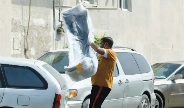  ?? Kamal Kassim/ Gulf Today ?? ↑
A man holds high equipment packed neatly in transparen­t bags to put them in the car’s boot.