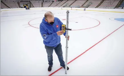  ?? The Canadian Press ?? Icemaker Greg Ewasko checks the ice at the WinSport’s Markin MacPhail Centre where the Scotties Tournament of Hearts will take place, in Calgary.