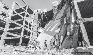  ?? MAHMUD HAMS / AGENCE FRANCE-PRESSE ?? Palestinia­n boys walk through the wreckage of a building that was damaged by Israeli air strikes the day before in Gaza City on Sunday.