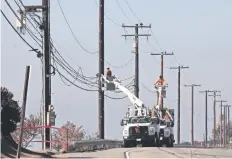  ??  ?? Cuadrillas de servicios públicos reparaban ayer el cableado en la autopista Pacific Coast, al oeste de Malibú, California, tras el paso del incendio Woolsey.