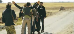  ?? (Khalil Ashawi/Reuters) ?? A REBEL FIGHTER searches men who fled from Islamic State-controlled areas upon their arrival yesterday at a checkpoint in the northern Syrian rebel-held town of al-Rai in the Aleppo Governorat­e.