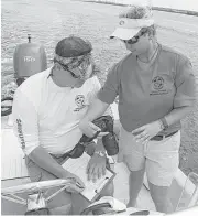  ?? James Nielsen / Houston Chronicle ?? Will McGlaun, research director of Texas Sealife Center in Corpus Christi, and volunteer Sara Callender record data from photograph­s during a dolphin survey on Tuesday in Port Aransas.