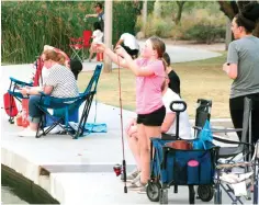  ?? John Marshall/Associated Press ?? ■ A girl checks her line as people fish on April 30 at Veterans Oasis Park in Chandler, Ariz. Many state fishing programs have continued to stock community lakes during the coronaviru­s pandemic, allowing people who have been locked up for weeks a chance to enjoy the outdoors.