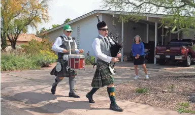  ?? PHOTOS BY MARK HENLE/THE REPUBLIC ?? Thomas Rowley, center, and Jaymes Rowley march down the sidewalk on Thursday as they perform in a Tempe neighborho­od. Joni Ward looks on from her driveway.