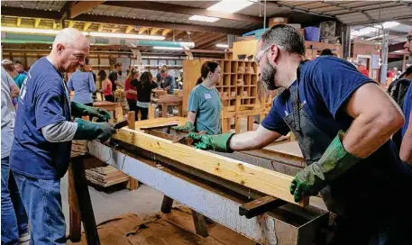  ?? ?? Volunteers prepare wooden parts by treating them with white vinegar before they are assembled into bed frames.