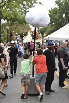  ?? JOHN RENNISON, HAMILTON SPECTATOR FILE PHOTO ?? Surprise, you’re on camera. Spec staffer Jeremy Kemeny, centre right with a Blue Jays hat, was captured while working Supercrawl 2016. Also captured: two boys taking Donna Akrey’s movable art installati­on, Cloud, for a spin.