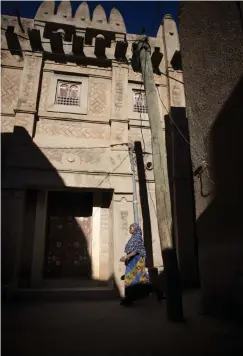  ??  ?? NYBYGGE. En kvinna passerar ett nybyggt hus som bryter mot Unescos riktlinjer. Stilen är traditione­ll men lerstenarn­a är ungnsbränd­a och fogade med cement.