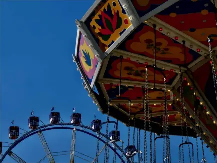  ??  ?? Blauer Himmel ist immer ein optimaler Hintergrun­d für ein Riesenrad. Das Kettenkaru­ssell
wirkt wie ein Durchblick und füllt die leere Fläche mit seiner plakativen Farbigkeit.