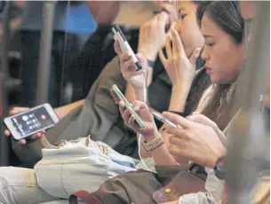  ?? APICHIT JINAKUL ?? Bangkok BTS Skytrain commuters spend time browsing on their mobile phones.