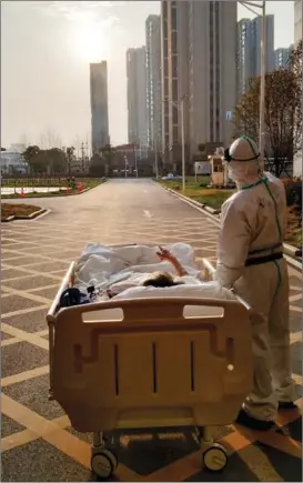  ?? GAN JUNCHAO / FOR CHINA DAILY ?? Wang Xin, an 87-year-old COVID-19 patient and his volunteer doctor, Liu Kai, watch the sunset on their way back from a CT scan on March 5, 2020, at Renmin Hospital of Wuhan University in Hubei province.