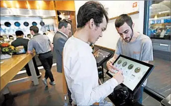  ?? CHARLES KRUPA/AP ?? Charles Renwick, right, lead software engineer at Spyce Food Company, helps a customer with an order last week.