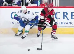  ?? — GETTY IMAGES ?? Nikolay Goldobin of the Canucks and Nick Cousins of the Coyotes battle for the puck during the second period on Thursday in Glendale, Ariz.