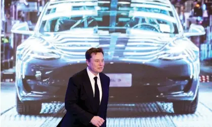  ?? ?? Elon Musk in front of a screen showing a Tesla Model 3 car, in January 2020. Photograph: Aly Song/Reuters