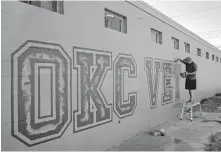  ??  ?? Ace Walker paints the logo of the new OKC Vet Campus at 601 W Reno Ave. The facility will open June 1 and offer services as a veterinari­an clinic, boarding kennels, training and day care, pet store, grooming and bath salon and agility training.