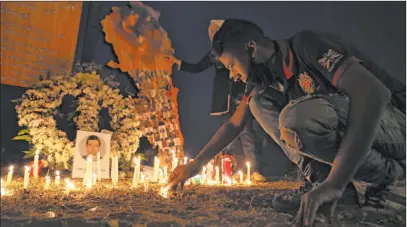  ?? Bilal Hussein The Associated Press ?? A man lights a candle Friday near the seaport in Beirut, Lebanon, to mark one month since the devastatin­g Aug. 4 explosion. People throughout Lebanon observed a moment of silence Friday, while rescuers dug through rubble, hoping to find a survivor.