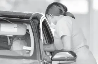  ??  ?? Spector Scientific Lab mobile phlebotomi­st Shernetta Bryant swabs a man for COVID-19 at a drive-through free testing site in the parking lot of Cheetah Gentleman’s Club in Pompano Beach on Sept. 29.