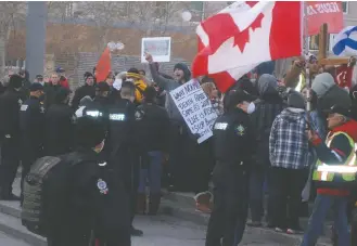  ?? CP PHOTO ROB DRINKWATER ?? Police and sheriffs look on as people participat­e in an anti-lockdown protest at the Alberta Legislatur­e in Edmonton on Saturday, February 20, 2021. Dozens of police and sheriffs kept hundreds of opponents of Alberta’s pandemic restrictio­ns separated from a anti-racism demonstrat­ors at the province’s legislatur­e on Saturday.