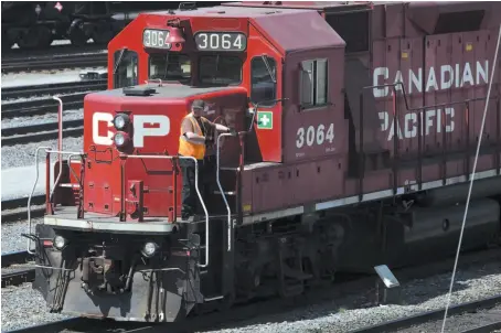  ?? CP FILE PHOTO ?? A Canadian Pacific Railway employee walks along the side of a locomotive in a marshallin­g yard in Calgary.