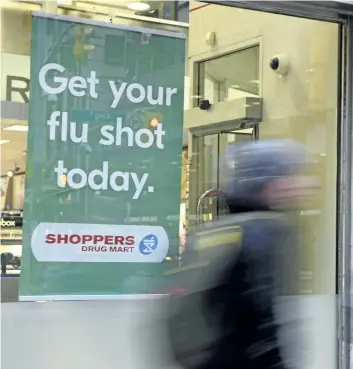  ?? DOUG IVES/ THE CANADIAN PRESS ?? People walk pass a sign for flu shots in Toronto on Tuesday. In its weekly FluWatch report, the Public Health Agency of Canada says there were 11,277 laboratory- confirmed cases of flu across the country as of Dec. 30.
