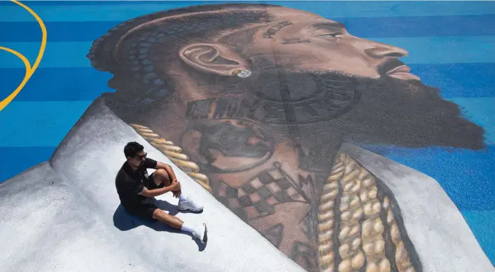  ??  ?? In this 17 April 2019 file photo, mural artist Gustavo Zermeno Jr. poses for photos on a basketball court mural he dedicated to slain rapper Nipsey Hussle in Los Angeles. Hussle, 33, was shot and killed outside his Los Angeles clothing store in Los Angeles on 31 March 2019. A year after Hussle’s death, his popularity and influence are as strong as ever. He won two posthumous Grammys in January, he remains a favourite of his hip-hop peers and his death has reshaped his hometown of Los Angeles in some unexpected ways. Photo: AP