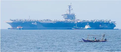  ?? AP ?? Fishermen pass by the USS Carl Vinson aircraft carrier at anchor off Manila, Philippine­s, for a five-day port call along with guided-missile destroyer USS Michael Murphy, on Saturday.