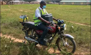  ?? ?? Bawa rides on a motorbike while carrying a box of AstraZenec­a covid-19 vaccine.