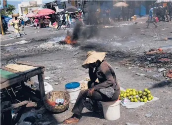  ?? MATIAS DELACROIX/AP ?? A tire burns as vendors work in a market left empty due to a general strike Monday in Port-au-Prince, Haiti. Worker unions and residents called for a strike to demand the end of violence and insecurity in the streets. Meanwhile, the FBI is still helping Haitian authoritie­s hunt for 16 Americans and one Canadian kidnapped by a gang more than a week ago.