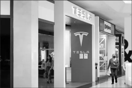  ?? KEITH SRAKOCIC / AP ?? People walk past the entrance to a Tesla store in February at a shopping mall in Pittsburgh. Tesla shares slumped about 3% in trading Monday after its CEO, Elon Musk, said he would sell 10% of his holdings — about $20 billion worth — in the electric car maker based on the results of a poll he conducted on Twitter over the weekend.