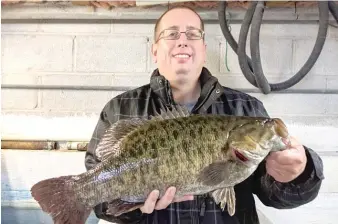  ?? DALE BOWMAN/FOR THE SUN-TIMES ?? ABOVE: Joe Capilupo with the Illinois-record smallmouth bass he caught Monday night at Monroe Harbor, photo taken the next morning at certificat­ion at Henry’s Sports and Bait.