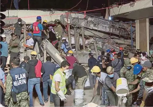 ?? - AFP ?? GAMBAR disiarkan pejabat Presiden Enrique Pena Nieto menunjukka­n orang ramai dan anggota penyelamat mencari mangsa di dalam runtuhan Sekolah Rendah Enrique Rebsamen di mana mayat sekurang-kurangnya 21 kanak-kanak ditemui.