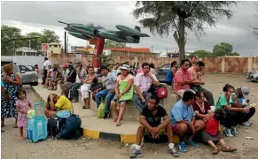  ??  ?? People wait at an air force base, above, to be evacuated after the floods closed all the roads in and out of Piura in northern Peru. A front-end loader, left, carries residents to safety after a massive landslide and flooding in the Huachipa district...