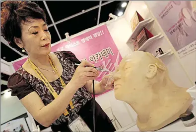  ?? AP/VINCENT YU ?? Lee Jong-lan, South Korea’s top funerary beautician, demonstrat­es her airbrushin­g technique for covering up discolored or damaged skin on corpses at the Asia Funeral and Cemetery Expo & Conference last week in Hong Kong.