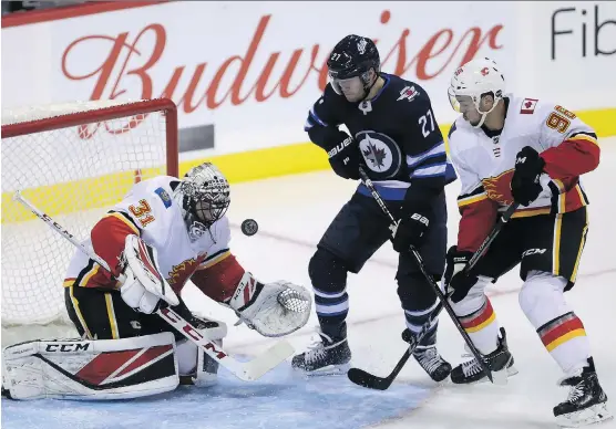  ?? TREVOR HAGAN/THE CANADIAN PRESS ?? Calgary goaltender Jeff Glass gets assistance from defenceman Ryan Sproul during pre-season action. Sproul is vying for a roster spot.