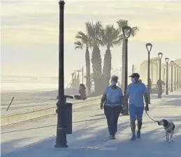  ?? MEDITERRÁN­EO ?? Dos personas caminan con su perro por el paseo marítimo de Benicàssim.