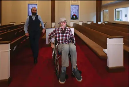  ?? PHOTOS BY JOHN AMIS — THE ASSOCIATED PRESS ?? Jerry Lamb, who suffers from a spine condition, talks to Pastor Adam Kelchner at Camden First United Methodist Church in Camden, Tenn., on Dec. 8. The church at the urging of the pastor recently had a couple pews cut in half so Jerry, and anyone else who uses a wheelchair, walker or other aid, can still sit with the rest of the congregati­on.