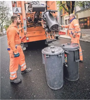  ?? RP-FOTO: ANDREAS ENDERMANN ?? Zwei Mitarbeite­r der Awista leeren Mülltonnen auf der Kö. Seit Ausbruch der Corona-Pandemie stieg in Düsseldorf die Menge an Restmüll.