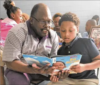  ?? COURTESY ?? Edward DuBose, who lives with the trauma of a harrowing bout with COVID-19, reads to his grandson, Seneca Allen. Over a year after surviving the disease, DuBose says he’s “nowhere near normal.”