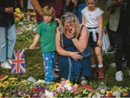  ?? EMILIO MORENATTI/AP ?? A woman weeps Saturday amid flowers and messages for Queen Elizabeth II, a rock in turbulent times, at the Green Park memorial near Buckingham Palace in London.