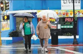  ?? GARY REYES — STAFF PHOTOGRAPH­ER ?? Luz Avellano, left, and Pati Cardenas return from a wet trip to the market along West Virginia Street in San Jose. The rain is expected to taper off Tuesday.