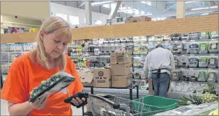  ?? KENN OLIVER/THE TELEGRAM ?? Personal shopper Janice Wells holds a pack of zucchini as she fills an online grocery order at the Memorial Stadium Dominion store on Tuesday, the first day the service was available in Newfoundla­nd. While just two stores currently offer the online...