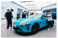  ?? Photo: AFP ?? People examine a Xiaomi SU7 electric car in a store in Beijing. The vehicle carries a starting price of 215,900 yuan.