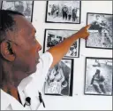  ??  ?? The Rev. Nelson Johnson points to a photo of himself checking on a fallen friend at his Faith Community Church in Greensboro, N.C.