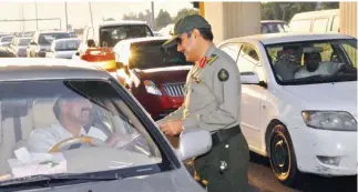  ??  ?? A security officer at a checkpoint along the Makkah-Jeddah Expressway checks the documents of a motorist.