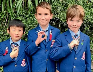  ??  ?? Wellesley College students Eric Zhang, Archie Lowe and Noah Baguley each hold a dollar coin over their vagus nerve. The students hope the simple symbol will go viral and help promote their Donate A Dollar Day campaign.