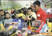  ?? AP/The Union/ELIAS FUNEZ ?? Kevin Cayabyab, a volunteer from The Church of Jesus Christ of Latter-day Saints, helps Tony Kidwell-Keisner, 5, pick out a toy during the weekend’s annual food and toy run at the Nevada County Fairground­s in Grass Valley, Calif.