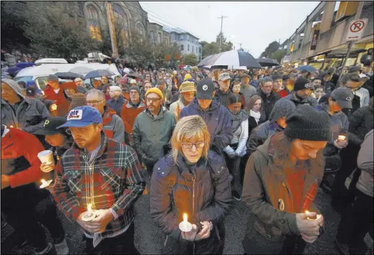  ?? Matt Rourke The Associated Press ?? People hold candles as they gather for a vigil Saturday in the aftermath of a deadly shooting at the Tree of Life Congregati­on in the Squirrel Hill neighborho­od of Pittsburgh.