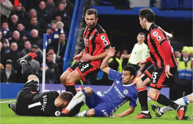  ??  ?? LONDON: Chelsea’s Spanish midfielder Pedro (CR) slides into Bournemout­h’s Polish goalkeeper Artur Boruc (L) during the English Premier League football match between Chelsea and Bournemout­h at Stamford Bridge in London yesterday. — AFP