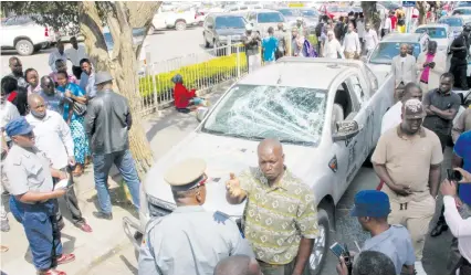  ?? — Picture by Innocent Makawa ?? Passers-by and police look at ZANU-PF Harare Province political commissar Shadreck Mayamombe's branded vehicle which was stoned by #Tajamuka members protesting the police clampdown on forex dealers in Harare yesterday.